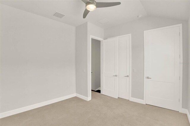 unfurnished bedroom featuring lofted ceiling, light colored carpet, and ceiling fan