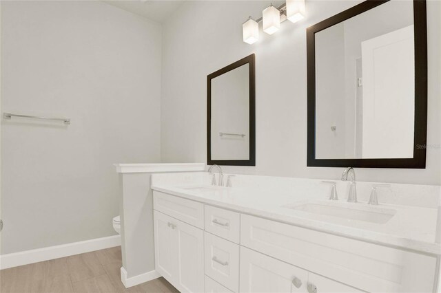 bathroom featuring dual vanity and toilet