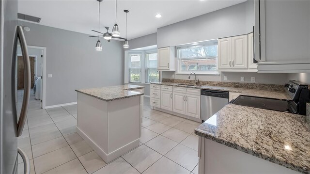 kitchen with stainless steel appliances, sink, light tile patterned floors, a center island, and ceiling fan