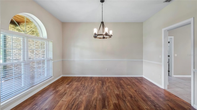 unfurnished dining area with hardwood / wood-style floors and a chandelier