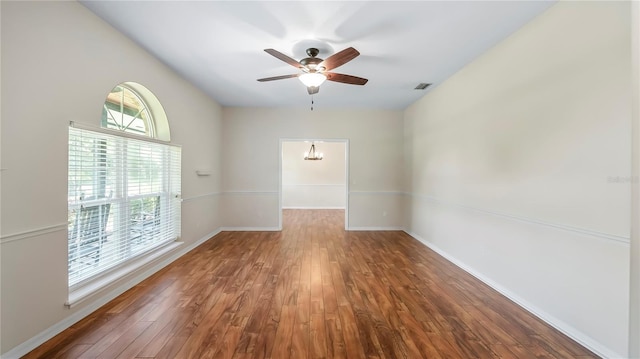 unfurnished room with ceiling fan with notable chandelier and hardwood / wood-style floors