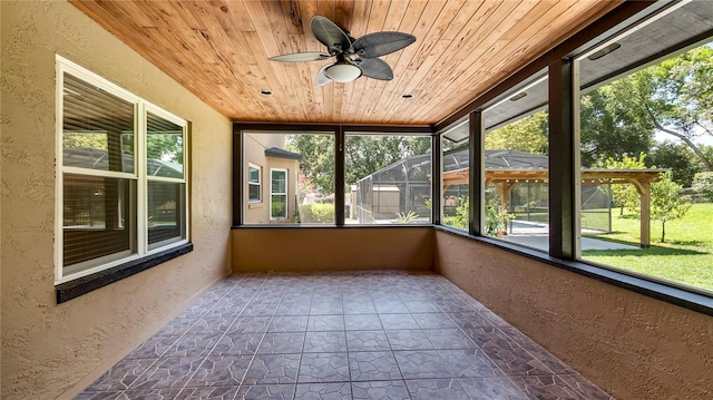 unfurnished sunroom with wood ceiling and ceiling fan