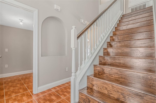 stairway featuring tile patterned flooring and a textured ceiling