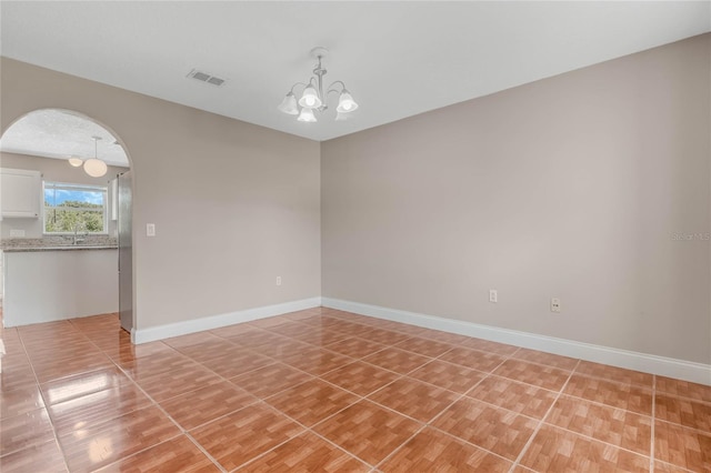 spare room featuring an inviting chandelier and light tile patterned floors