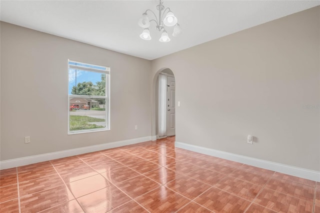 tiled spare room with a chandelier