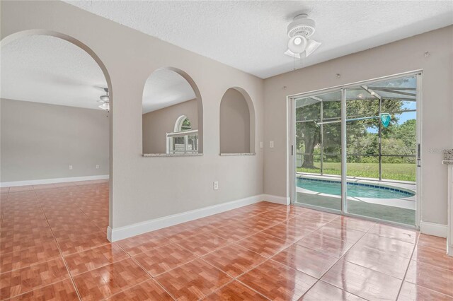 tiled empty room with a textured ceiling and ceiling fan