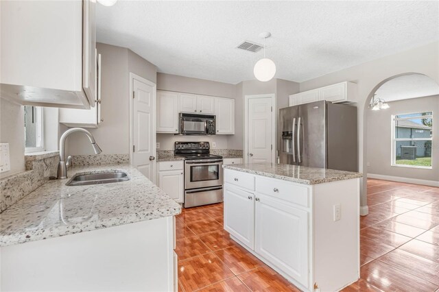 kitchen with stainless steel appliances, sink, light tile patterned floors, light stone countertops, and white cabinetry