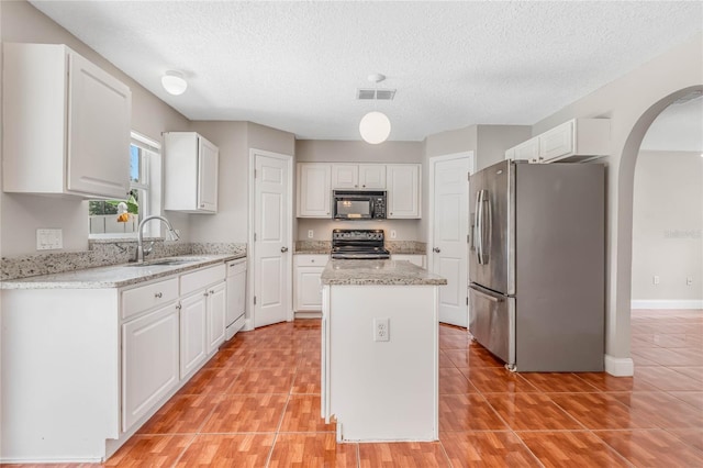 kitchen featuring a kitchen island, white cabinets, and stainless steel refrigerator