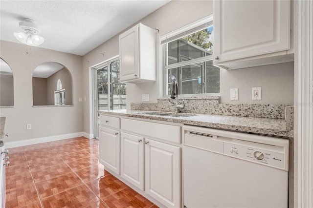 kitchen featuring sink, light tile patterned floors, dishwasher, white cabinetry, and a textured ceiling