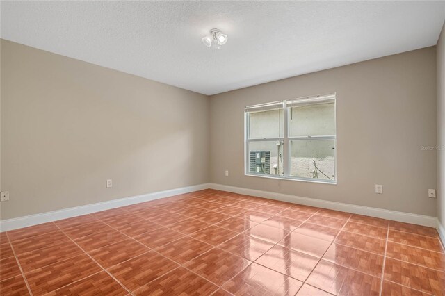 spare room featuring tile patterned flooring and a textured ceiling