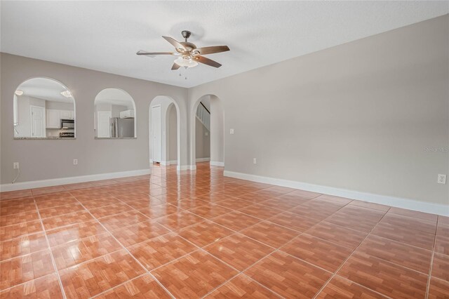 tiled spare room with a textured ceiling and ceiling fan