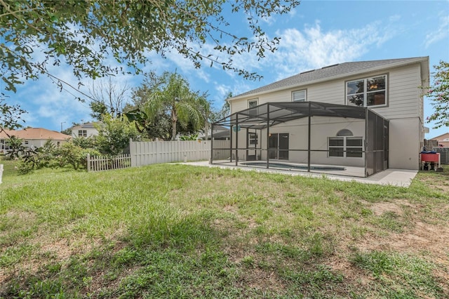 rear view of house featuring a lanai, a patio area, and a lawn