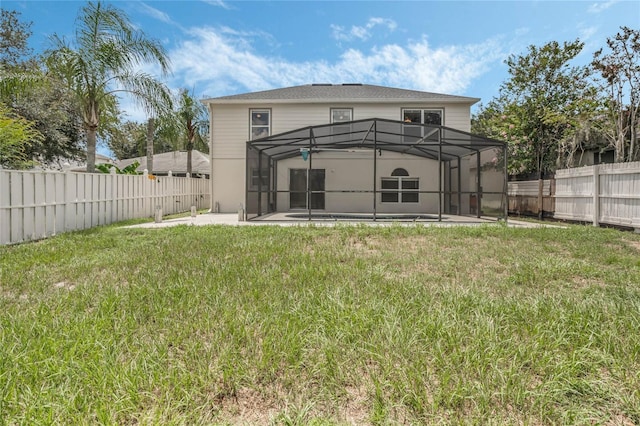 rear view of house with a lanai, a patio area, and a lawn