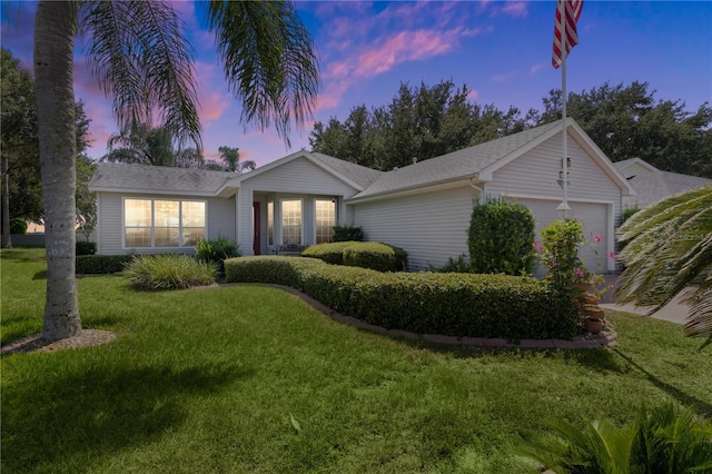 ranch-style home with a garage and a yard