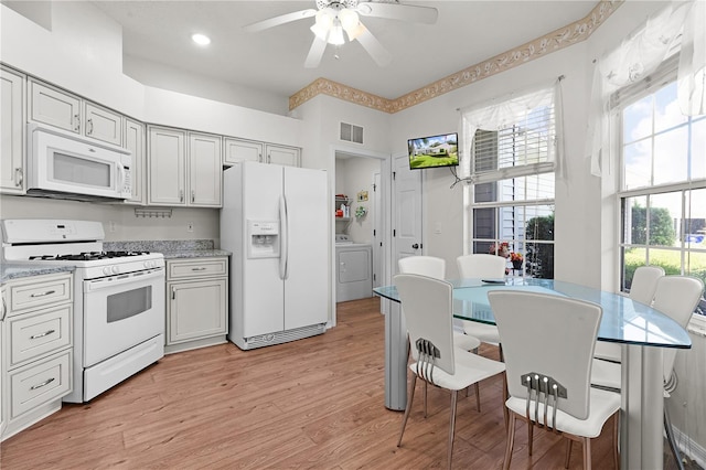 kitchen with ceiling fan, light stone counters, light hardwood / wood-style flooring, white appliances, and washer / dryer