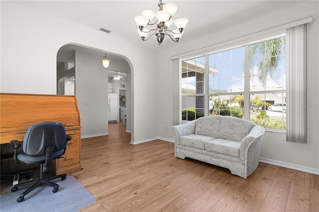 office with light hardwood / wood-style floors and ceiling fan with notable chandelier