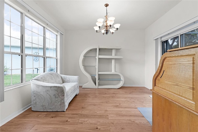 living area featuring a healthy amount of sunlight, light wood-type flooring, and an inviting chandelier