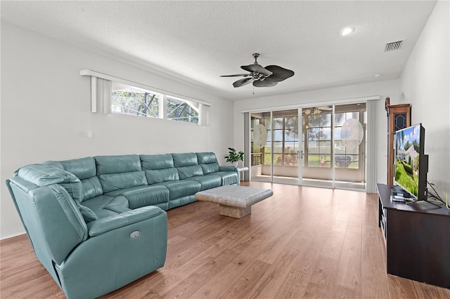 living room with a healthy amount of sunlight, ceiling fan, light hardwood / wood-style floors, and a textured ceiling