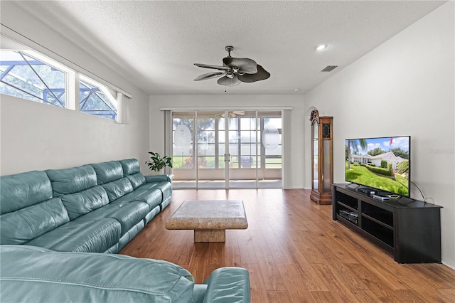 living room with light wood-type flooring, a textured ceiling, a wealth of natural light, and ceiling fan