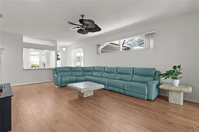 living room with a textured ceiling, light hardwood / wood-style floors, and ceiling fan