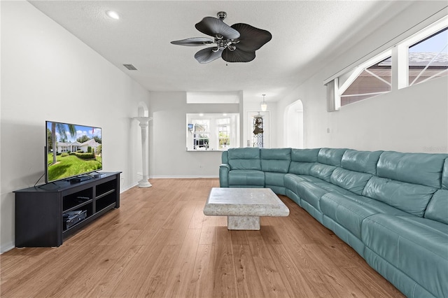 living room with a textured ceiling, light hardwood / wood-style flooring, a wealth of natural light, and ceiling fan