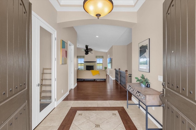 foyer featuring a fireplace, a ceiling fan, baseboards, vaulted ceiling, and tile patterned floors