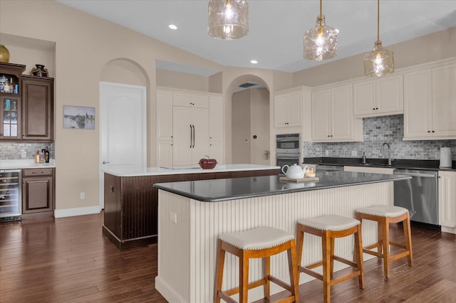 kitchen featuring appliances with stainless steel finishes, a center island, beverage cooler, and a sink