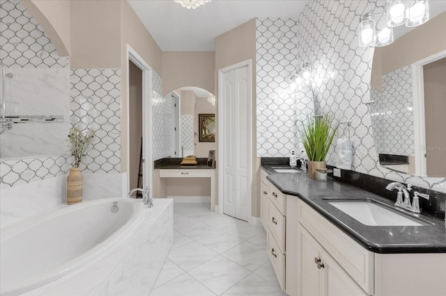 full bath with a garden tub, marble finish floor, double vanity, and a sink