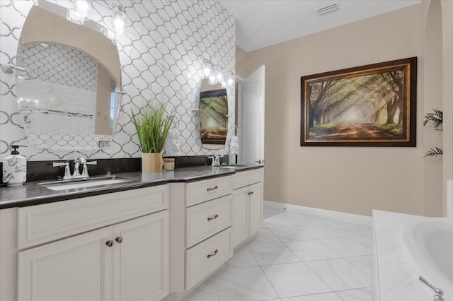 bathroom with double vanity, a sink, visible vents, and baseboards