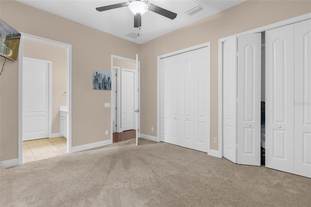 unfurnished bedroom with baseboards, visible vents, connected bathroom, carpet flooring, and two closets