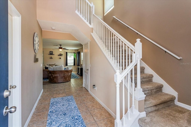 staircase featuring a towering ceiling, tile patterned floors, and ceiling fan