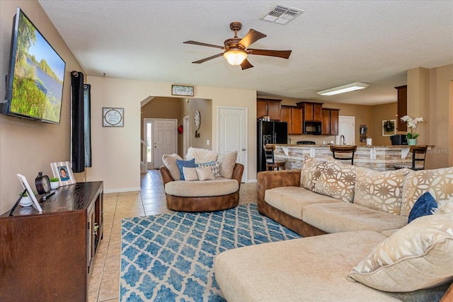 living room with light tile patterned floors, a textured ceiling, and ceiling fan