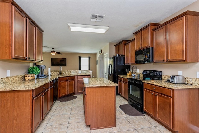 kitchen with a center island, light stone countertops, black appliances, light tile patterned flooring, and kitchen peninsula