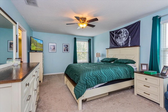 carpeted bedroom with ceiling fan and a textured ceiling