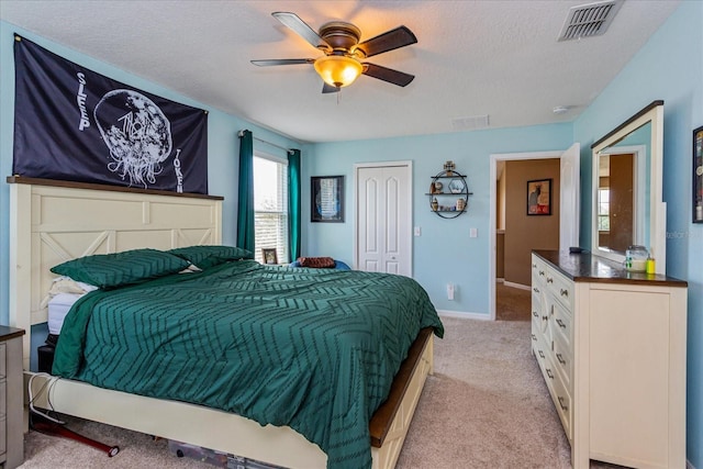 bedroom with light carpet, a textured ceiling, a closet, and ceiling fan