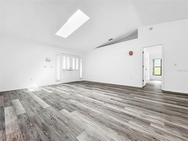 unfurnished living room featuring hardwood / wood-style flooring and vaulted ceiling with skylight