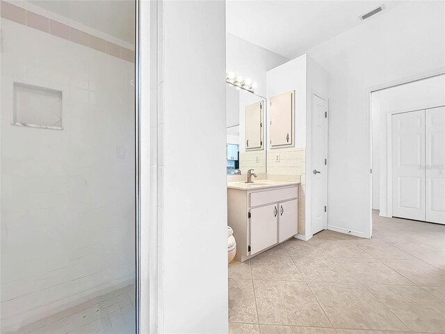 bathroom featuring vanity, decorative backsplash, tile patterned flooring, and toilet