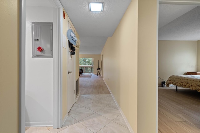 hall featuring electric panel, a textured ceiling, and light hardwood / wood-style flooring