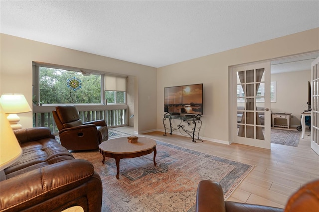 living room with french doors, a textured ceiling, and light wood-type flooring