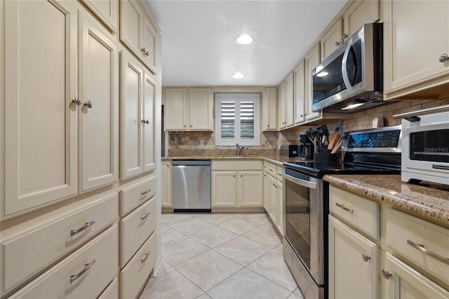 kitchen featuring appliances with stainless steel finishes, cream cabinets, decorative backsplash, and light tile patterned floors