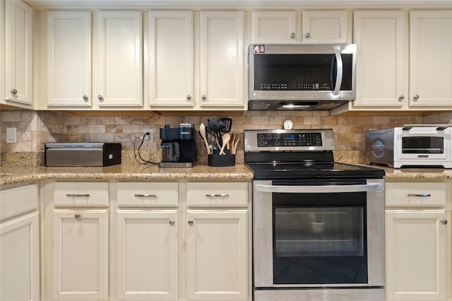 kitchen featuring appliances with stainless steel finishes, backsplash, and light stone counters