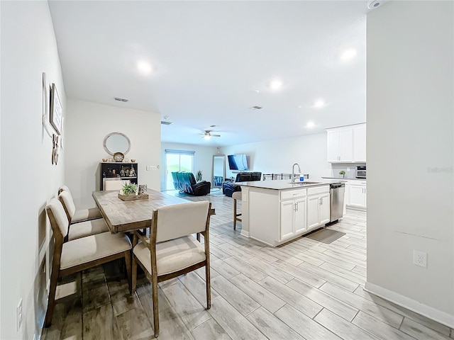 kitchen featuring white cabinets, sink, dishwasher, light hardwood / wood-style floors, and a kitchen island with sink