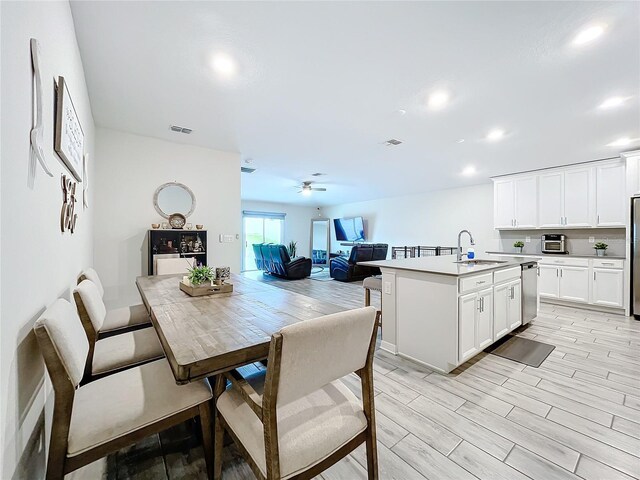 interior space featuring a center island with sink, dishwasher, light wood-type flooring, and sink