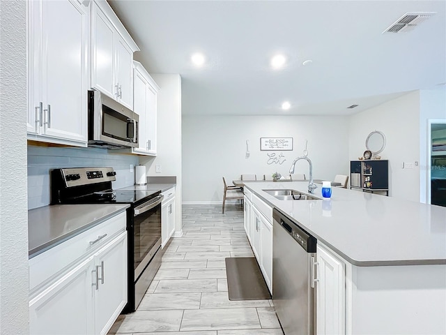 kitchen with light tile patterned flooring, stainless steel appliances, white cabinets, sink, and backsplash