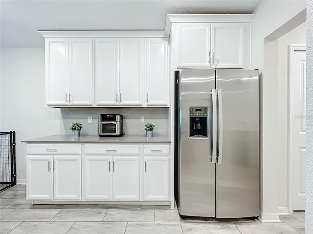 kitchen with decorative backsplash, white cabinets, light tile patterned floors, and stainless steel fridge with ice dispenser