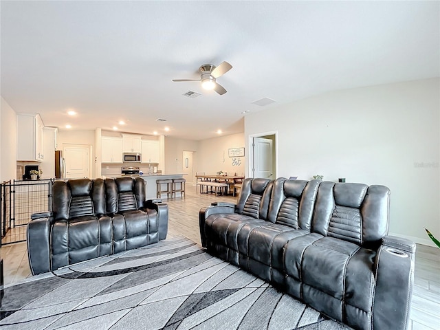 living room with light hardwood / wood-style floors and ceiling fan