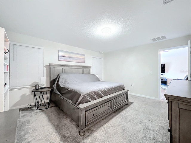 bedroom with light carpet and a textured ceiling