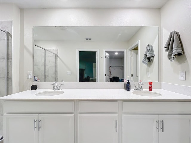 bathroom with dual vanity and a shower with shower door