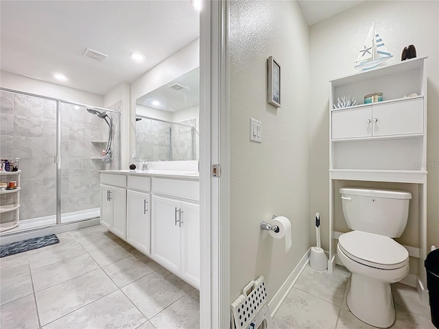 bathroom with vanity, tiled shower, toilet, and tile patterned floors