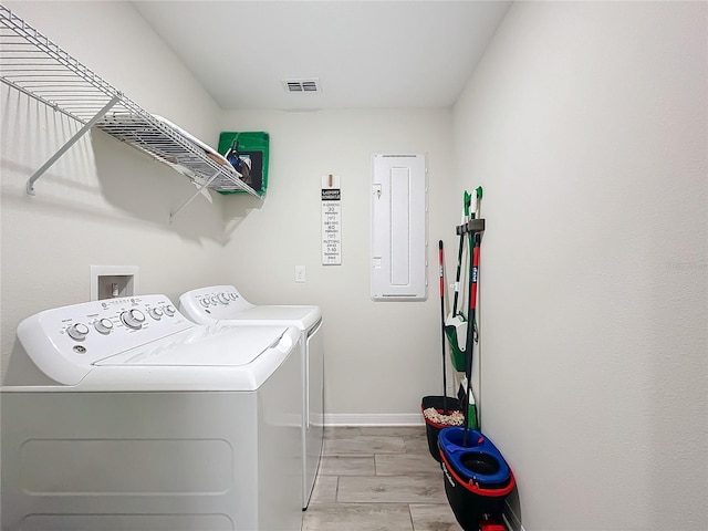 clothes washing area with light hardwood / wood-style floors, separate washer and dryer, and electric panel